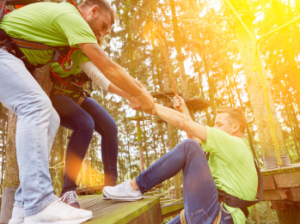 Participants helping one person climb an obstacle, demonstrating teamwork and leadership.