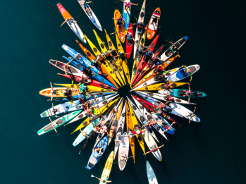 A group of kayaks arranged in a star or circle formation on the water.