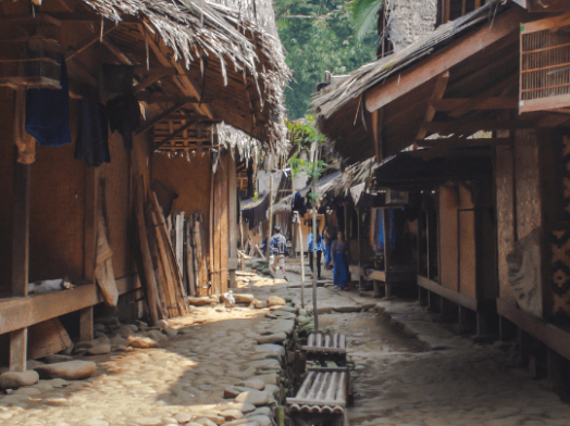 Traditional Indonesian village with thatched roofs and people in the background.